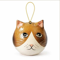 A cat-shaped ornament with a glossy brown and white painted face, black eyes, a small pink nose, and a gold hanging loop at the top