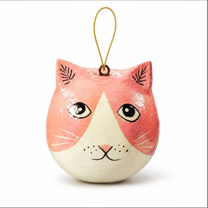 A cat-shaped hanging ornament with a pink and cream face, black painted details, and a gold hanging loop, shown on a plain white background.