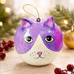 A round cat-shaped Christmas ornament with a purple and white painted design, featuring black eyes, a pink nose, and a gold hanging loop