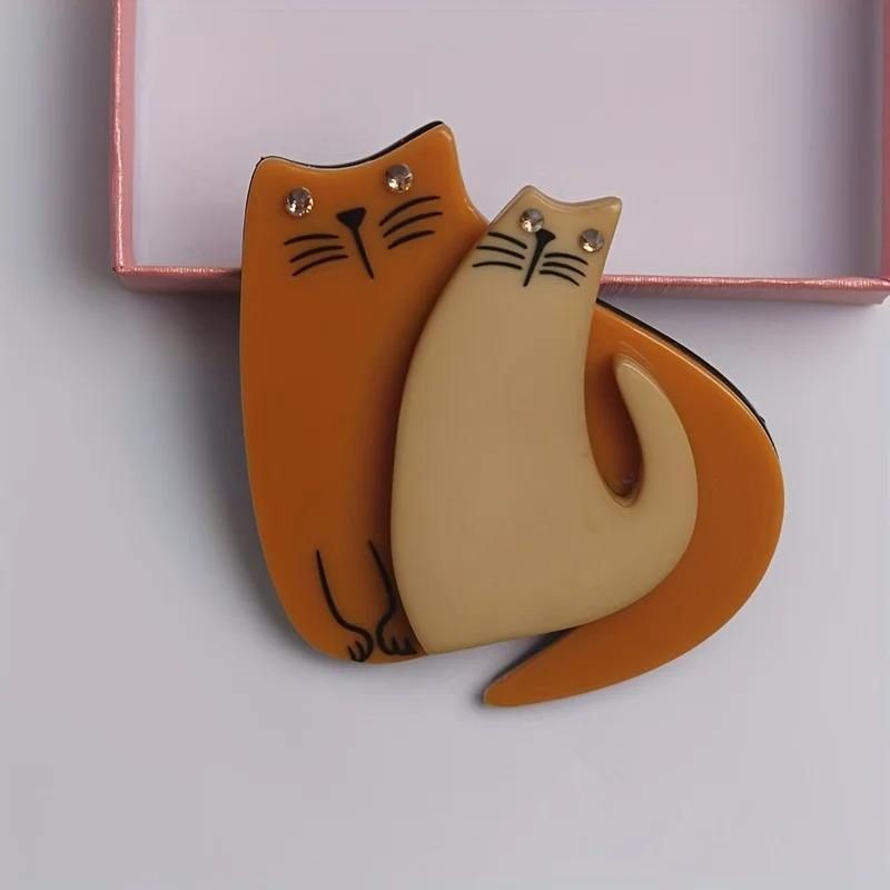 Cat-shaped orange brooch on a light grey background