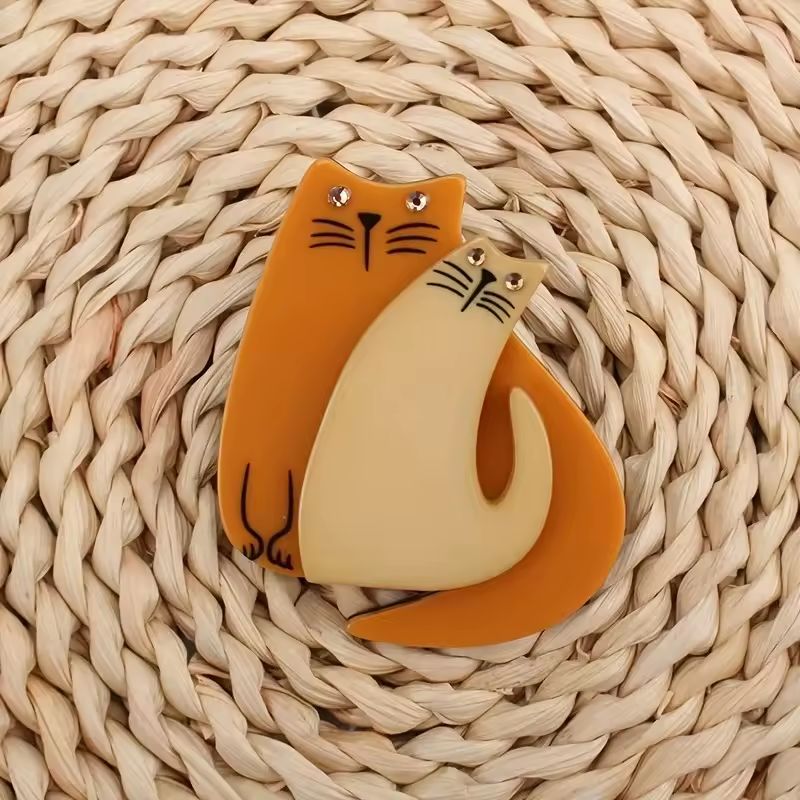 Cat-shaped orange and cream brooch on a woven surface