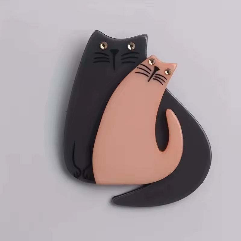 Two cat-shaped objects, one black and one pink, on a light gray background.