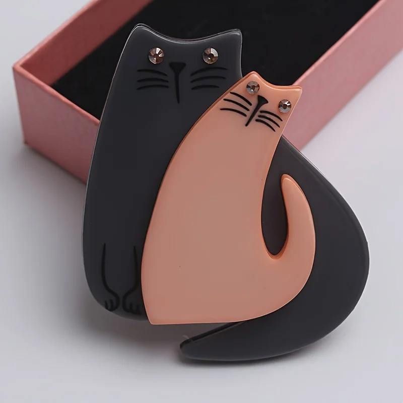Cat-shaped brooch with black and pink colours on a light grey background