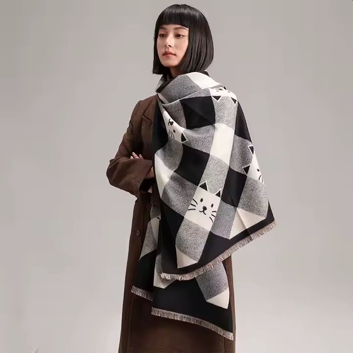 A woman wearing a large scarf with a black and white cat face geometric pattern