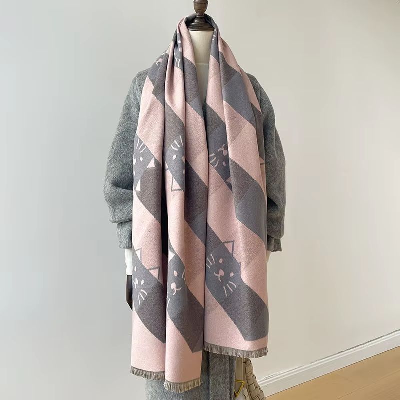 A scarf with grey and pink colours featuring cat face patterns displayed on a mannequin
