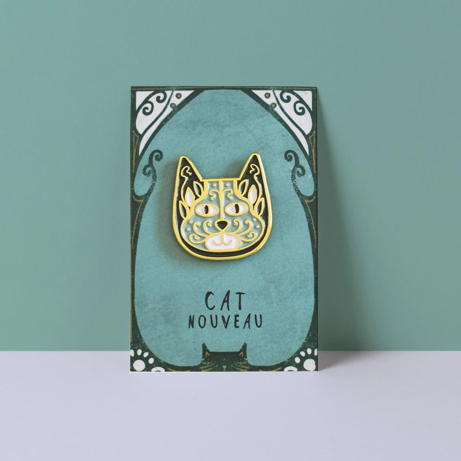 An enamel pin badge depicting a stylised cat face with a floral pattern on backing card labelled Cat Nouveau
