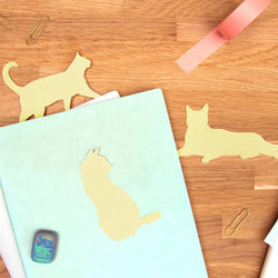 Notebook with cat-shaped cutouts on a wooden surface