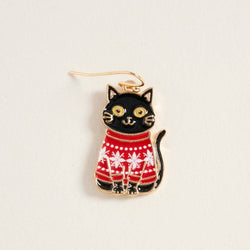 A black cat-shaped earring with gold-tone metal outlines, wearing a red and white patterned sweater