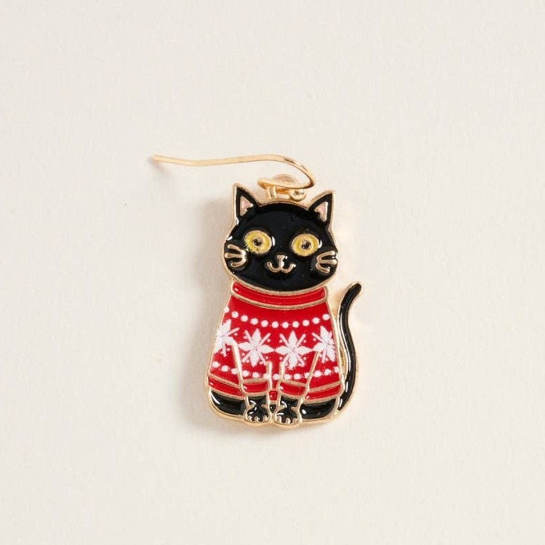 A black cat-shaped earring with gold-tone metal outlines, wearing a red and white patterned sweater