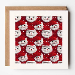 A square greeting card with a white border and kraft brown envelope, featuring a repeating pattern of white fluffy cat faces wearing red Santa hats on a red background.