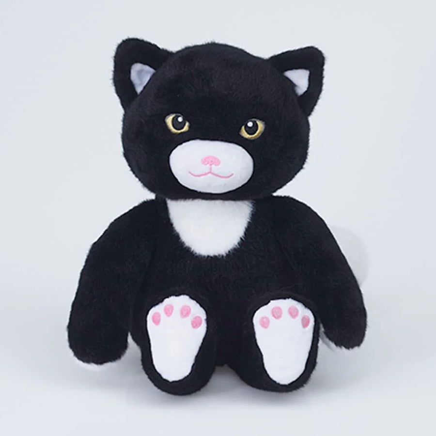 A black and white plush toy cat with embroidered yellow eyes, a pink nose, and pink paw pads