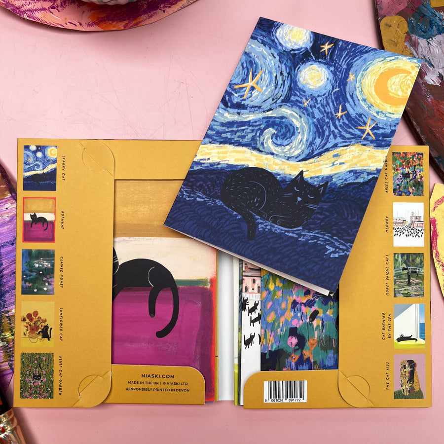 A flat-lay of notecards featuring a Van Gogh-style Starry Night cat illustration, displayed on top of its yellow cardboard backing