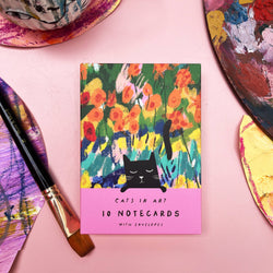 A flat-lay of a notecard wallet that features a colourful floral painting with a black cat silhouette 