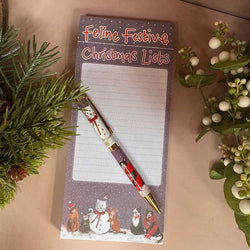 A festive Christmas-themed notepad titled 'Feline Festive Christmas Lists' with a matching pen featuring a snowman and cat illustration
