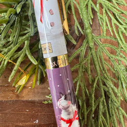 A close-up of a decorative pen with a white top section showing a snowy landscape and a purple lower section featuring a cat illustration