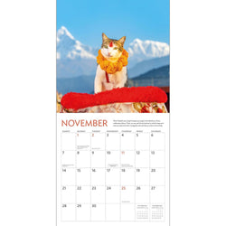 Calendar page for November with a cat wearing a flower crown and holding a red object, set against a mountainous background.