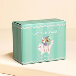 A mint green product box for 'Cat Bud Vase' by Lisa Angel, featuring a white cat illustration holding a bouquet of flowers, set against a warm beige background.