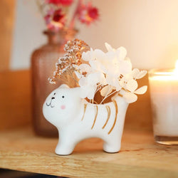Ceramic cat-shaped vase with flowers on a wooden surface