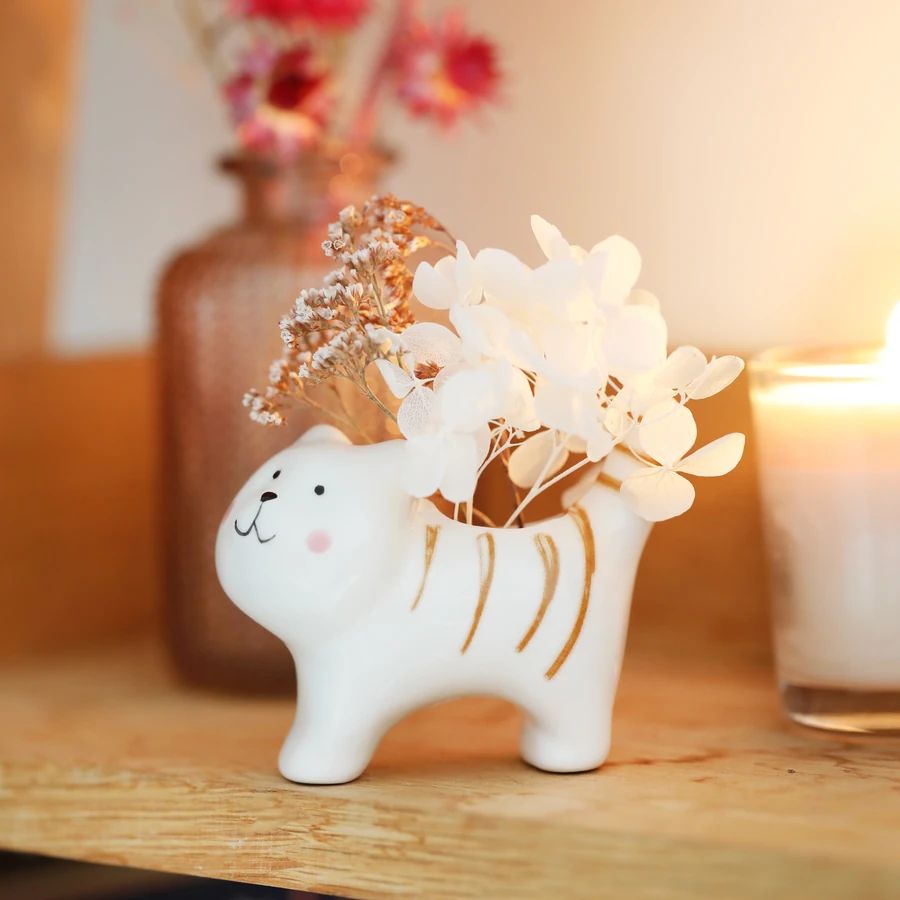 Ceramic cat-shaped vase with flowers on a wooden surface