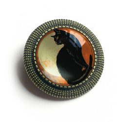 Round brooch with a black cat design on a white background