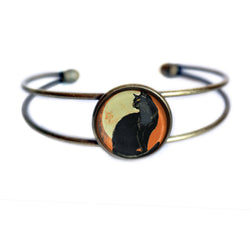 A double-band cuff bracelet with an antique bronze finish, featuring a circular central cabochon depicting a black cat silhouette
