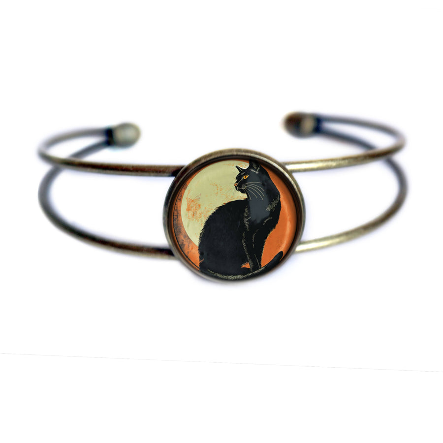 A double-band cuff bracelet with an antique bronze finish, featuring a circular central cabochon depicting a black cat silhouette