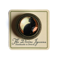 Black cat brooch on a card with 'The Divine Iguana' branding
