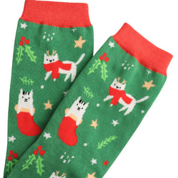 White festive cats on a green sock with background stars and foliage