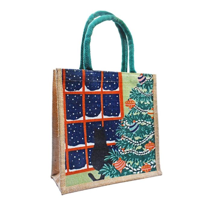A jute tote bag with teal fabric handles, featuring a printed Christmas-themed design on the front with a snowy window, a black cat silhouette, and a decorated Christmas tree.