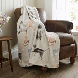 Blanket with cat pattern draped over a brown armchair in a room with wooden floor and window.