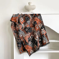 Decorative throw blanket with cat pattern draped over a chair against a white wall.