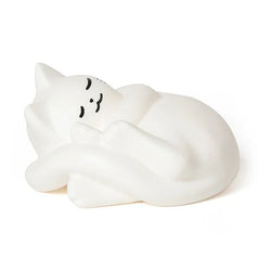 A white sleeping cat figurine with simple black line art for closed eyes and a small pink nose