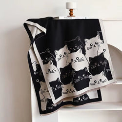 A scarf with black and white cat patterns displayed on a mannequin wearing a brown coat