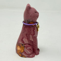 A marbled aubergine-coloured lucky cat figurine wearing a purple collar with a gold letter 'P' charm, set against a plain light grey background. Side view.