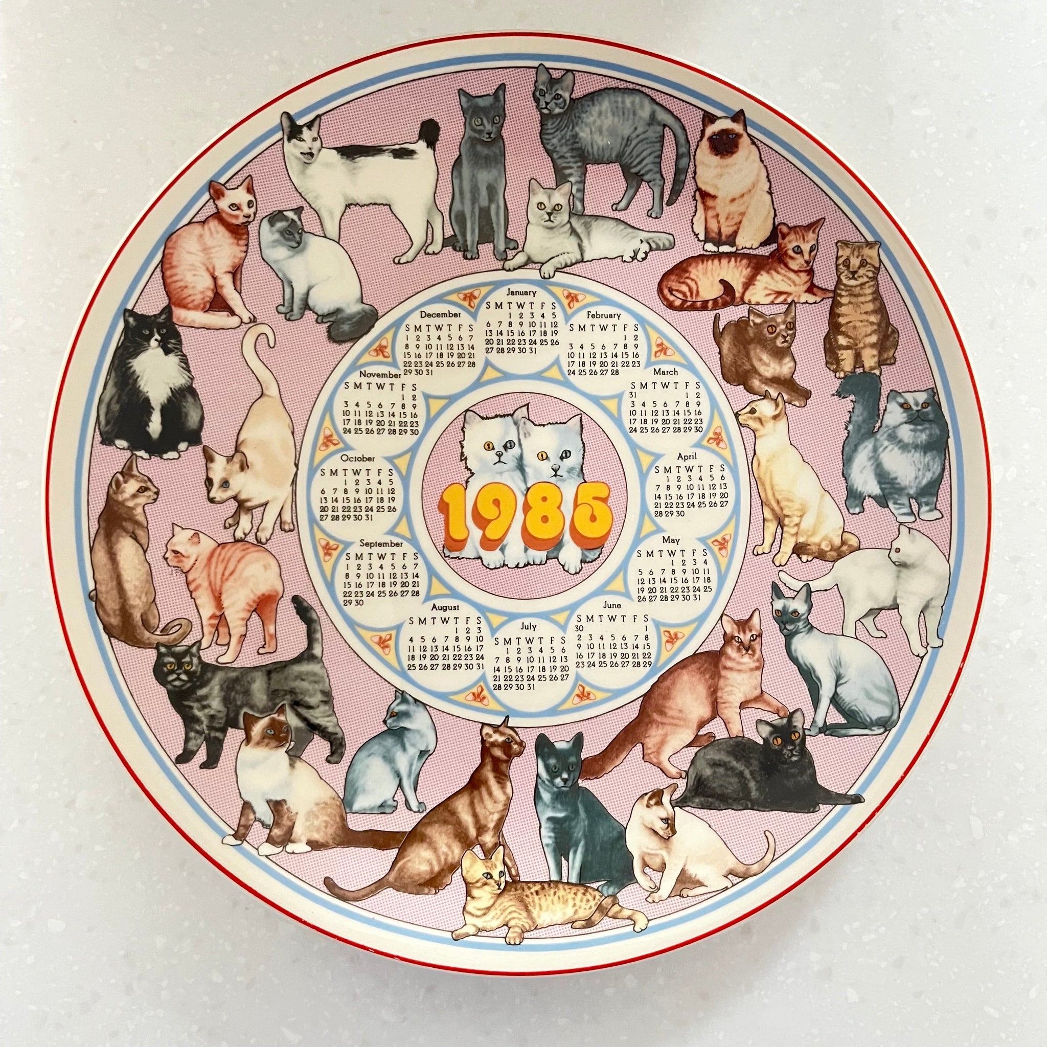 Circular calendar with illustrations of cats and a central design, featuring the year 1985.