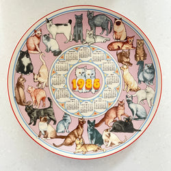 Circular calendar with illustrations of cats and a central design, featuring the year 1985.