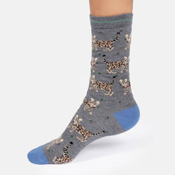 A single grey crew sock with an allover bengal cat print and solid blue toe and heel, shown on a foot 