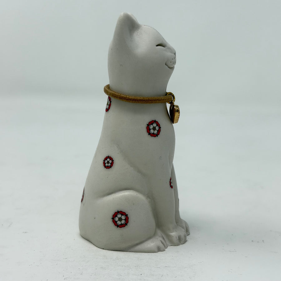 A white resin lucky cat figurine with a brown collar, red heart charm and Yorkshire Rose decoration - side view