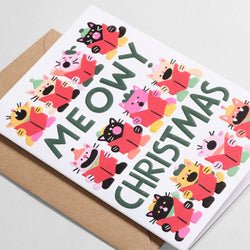 A white Christmas greeting card with the words 'MEOWY CHRISTMAS' in large dark green letters, surrounded by colorful cartoon cat characters in red, pink, yellow, and black clothing. 