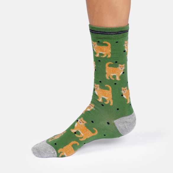 A single crew sock worn on a foot, featuring a green background with an all over pattern of orange tabby cats and small black dots