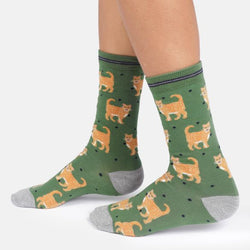 A pair of crew socks, featuring an all-over print of orange tabby cats on a muted green background with small black polka dots