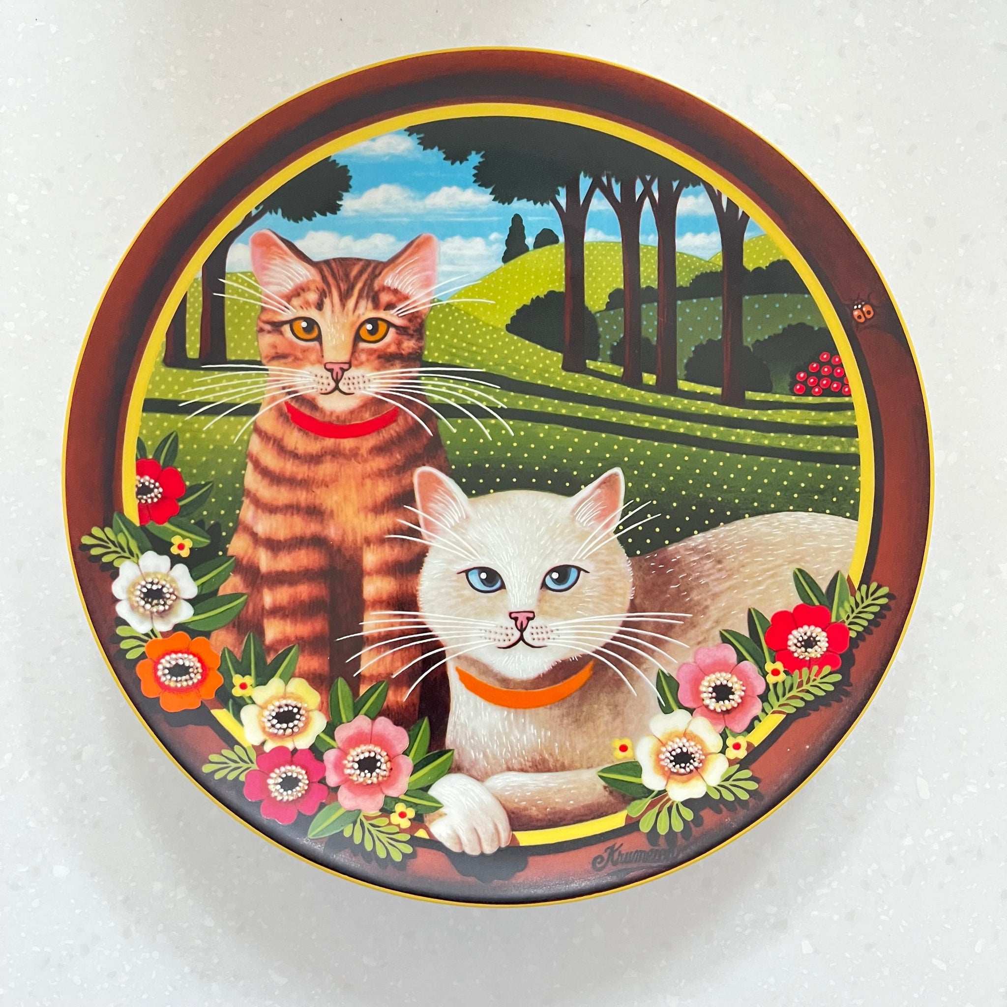 Decorative plate with two cats and floral designs on a white background