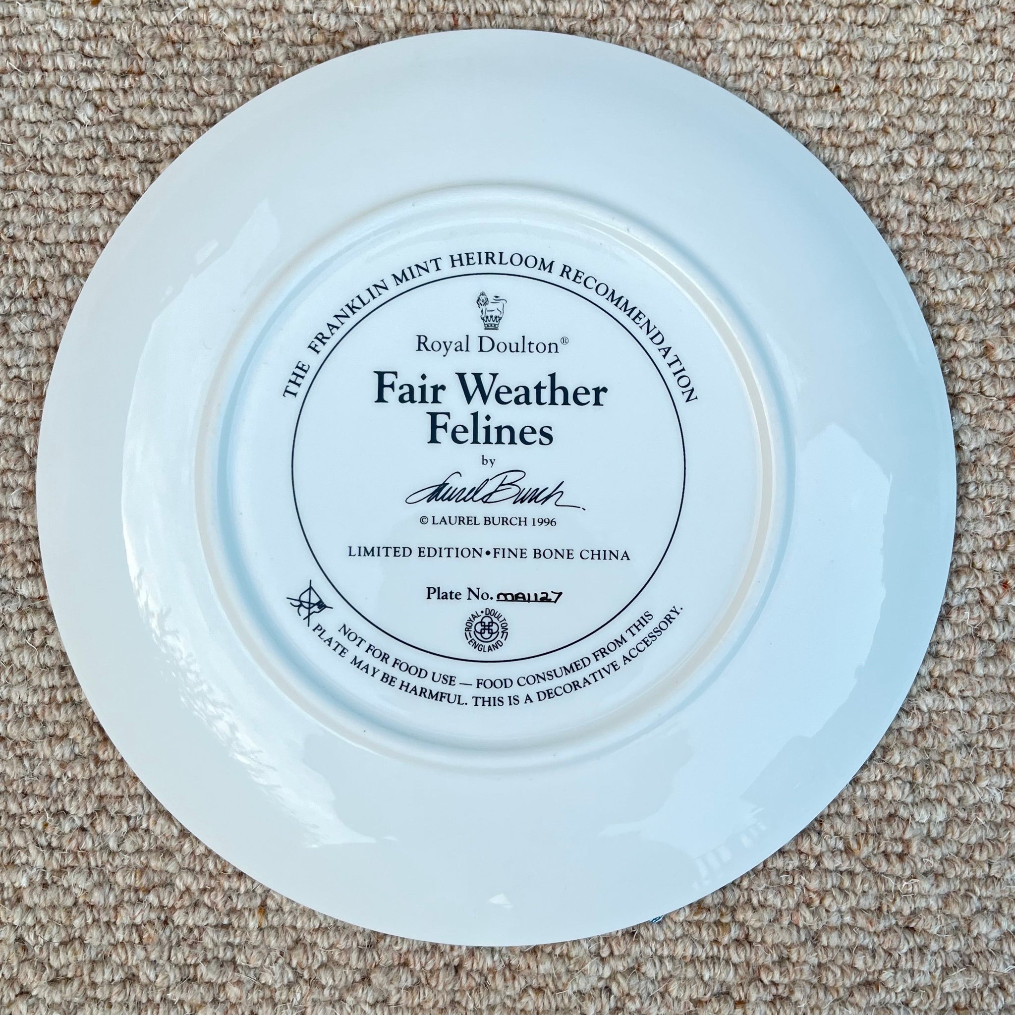 Round plate with 'Fair Weather Felines' branding on a beige carpet