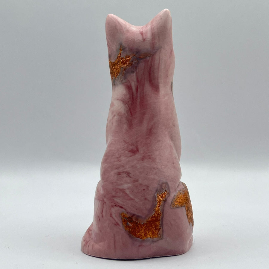 A pink cat figure, featuring natural pink stone marbling and textured metallic gold inclusions, shown against a neutral grey background.