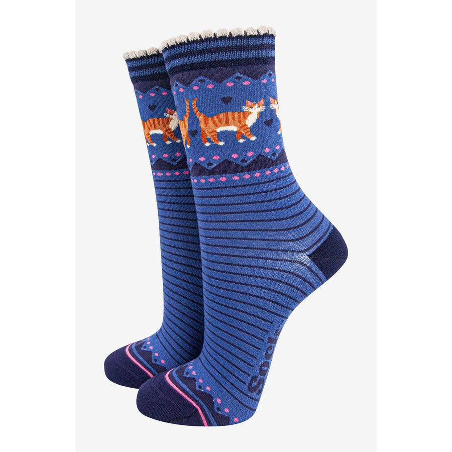 A pair of blue crew socks with a pattern of orange tabby cats, hearts, and geometric shapes