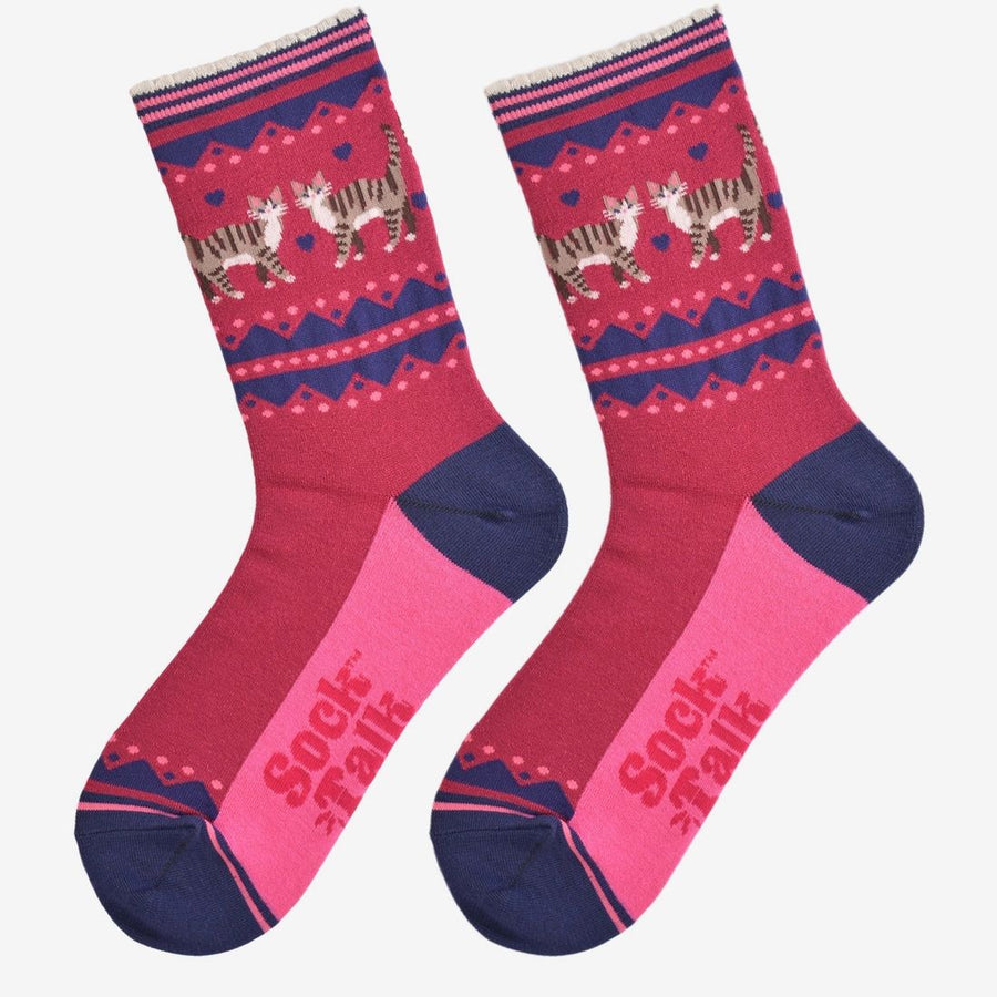 A pair of crew socks featuring a pink and navy blue Nordic pattern with walking cat illustrations