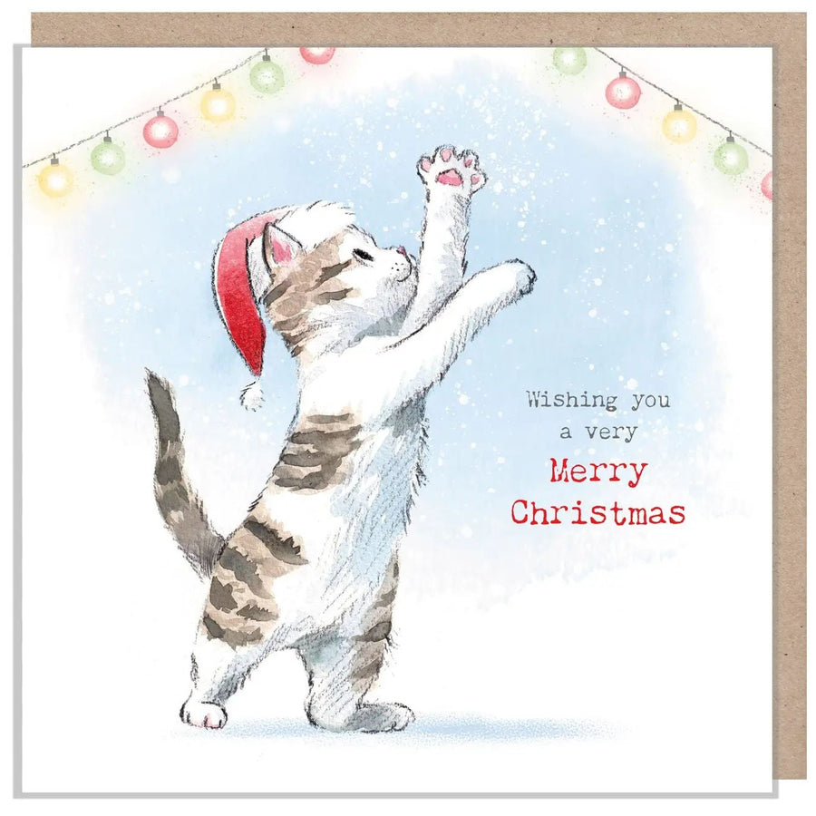 A square Christmas greeting card featuring a tabby cat wearing a red Santa hat and reaching upward against a light blue snowy background