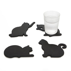 Four black cat-shaped coasters with a glass on one of them against a white background