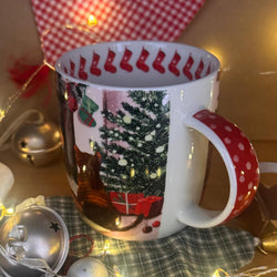 A white ceramic mug with a Christmas-themed print featuring a cat, Christmas tree, stockings, and red polka-dot handle