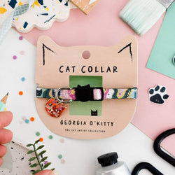 A colourful patterned cat collar with a small cat-shaped charm is displayed on a beige cardboard card labelled 'GEORGIA O'KITTY'